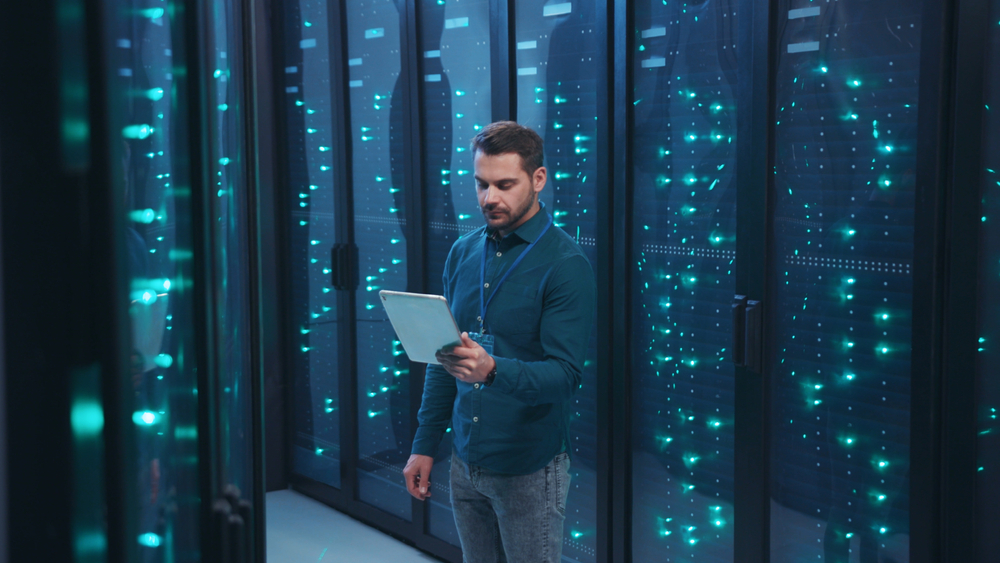 A man in a server room holding a tablet