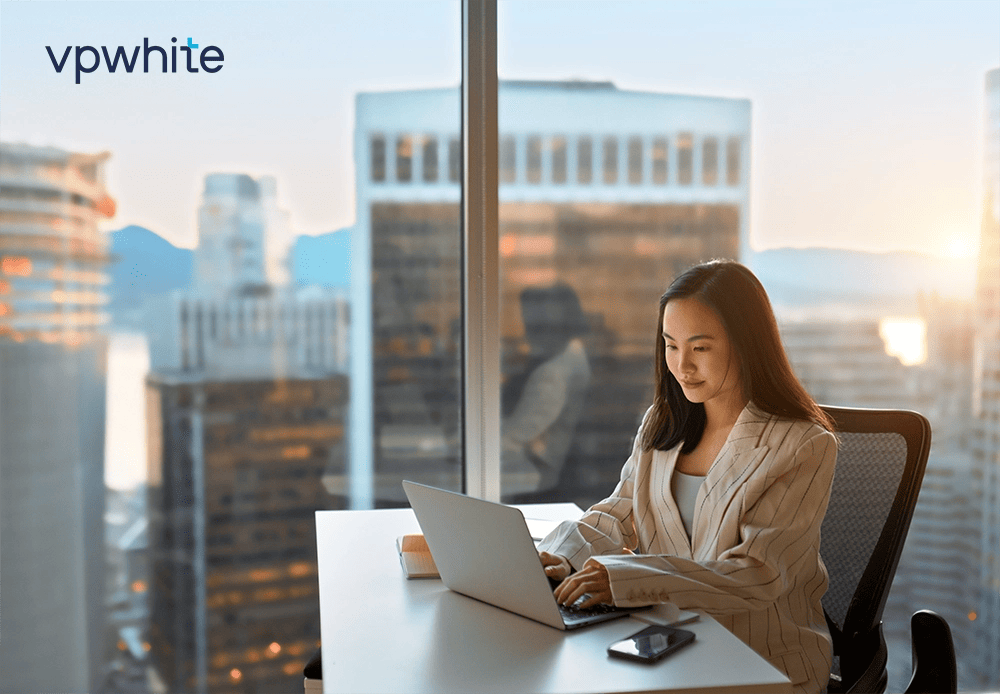Illustration femme assise à un bureau avec logo VPWhite en haut à gauche