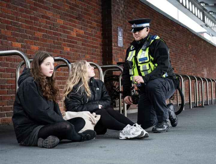 A British Transport Police officer speaking supportively with two vulnerable young people at a railway station, illustrating the critical role of frontline staff in safeguarding and early intervention.