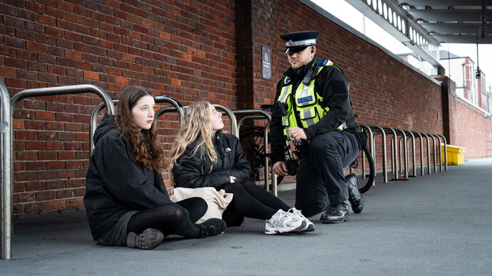 A British Transport Police officer speaking supportively with two vulnerable young people at a railway station, illustrating the critical role of frontline staff in safeguarding and early intervention.